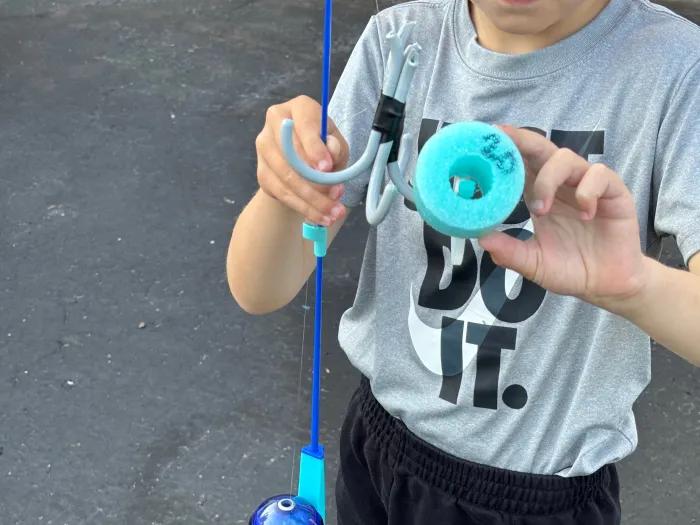 boy holding up pool noodle piece with number 20 on bottom