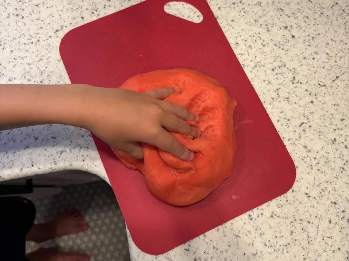boy's hand on red dough ball