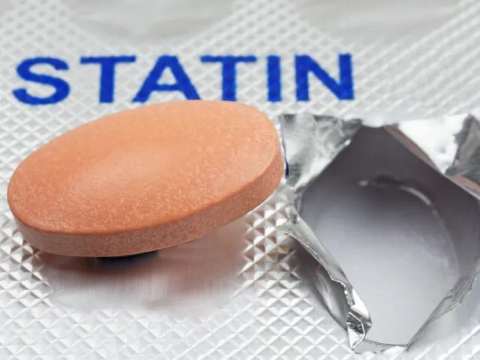 word statin in capital letters blue and pill out of silver case