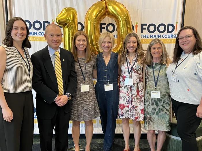 team smiling together in front of 10 year anniversary sign