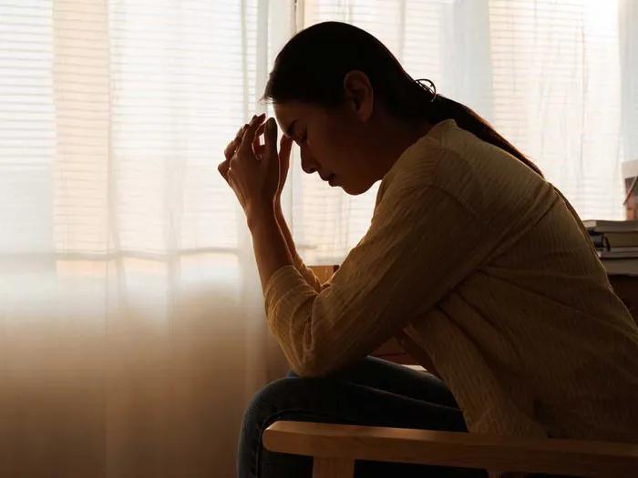 Woman sits with head in hands