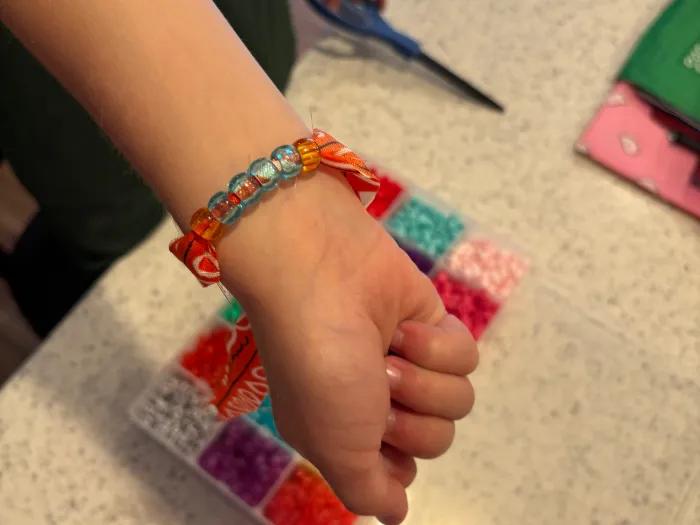 boy showing orange bracelet on wrist with blue beads