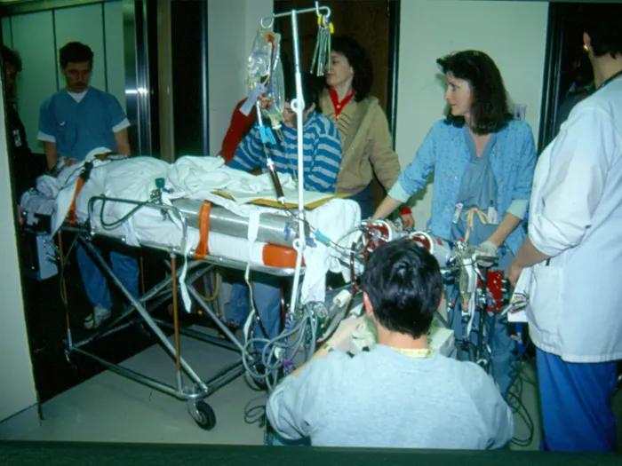 Patient on stretcher taking the elevator with a lot of physicians around