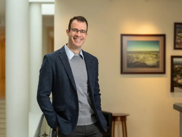 Dr. Seth Waits wearing a dark blazer and gray sweater with a collar. 