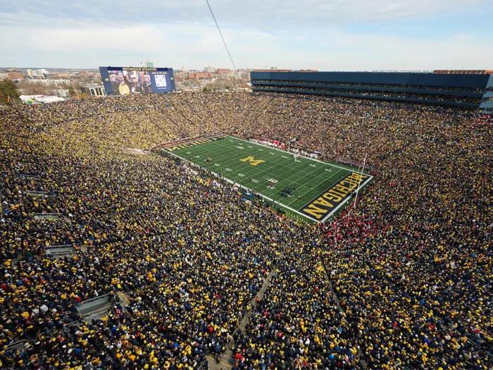 Filled U-M football stadium on a sunny day aerial 