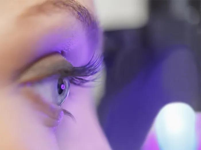 Eye and eyebrow with purple light shining on it