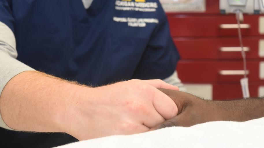 No One Dies Alone image of patient holding staff hand.