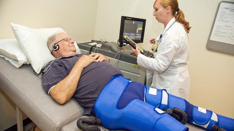 Reclining patient attached to compression pants and monitor for EECP treatment