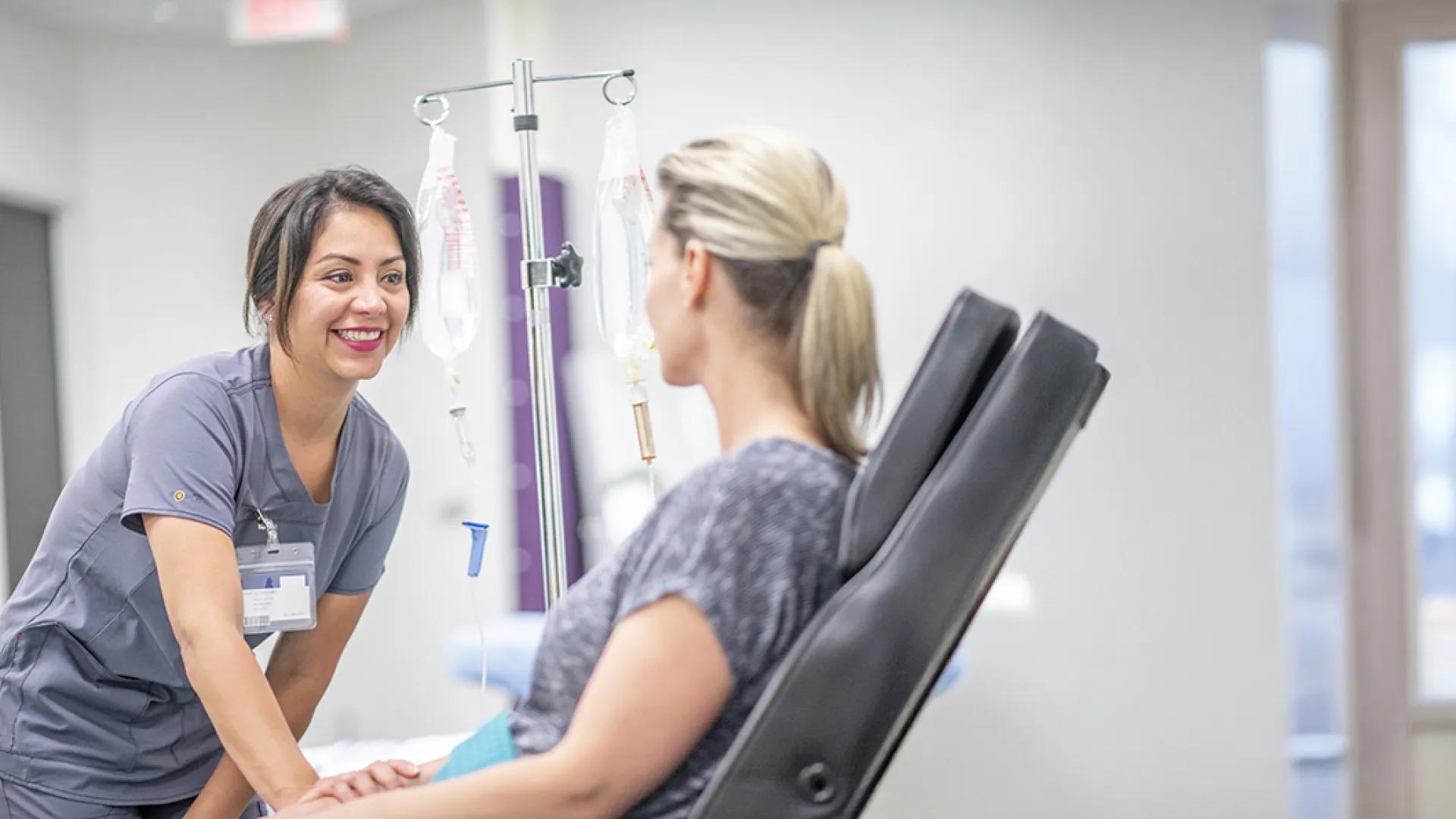 Infusion tech talking to a patient sitting in an infusion chair.