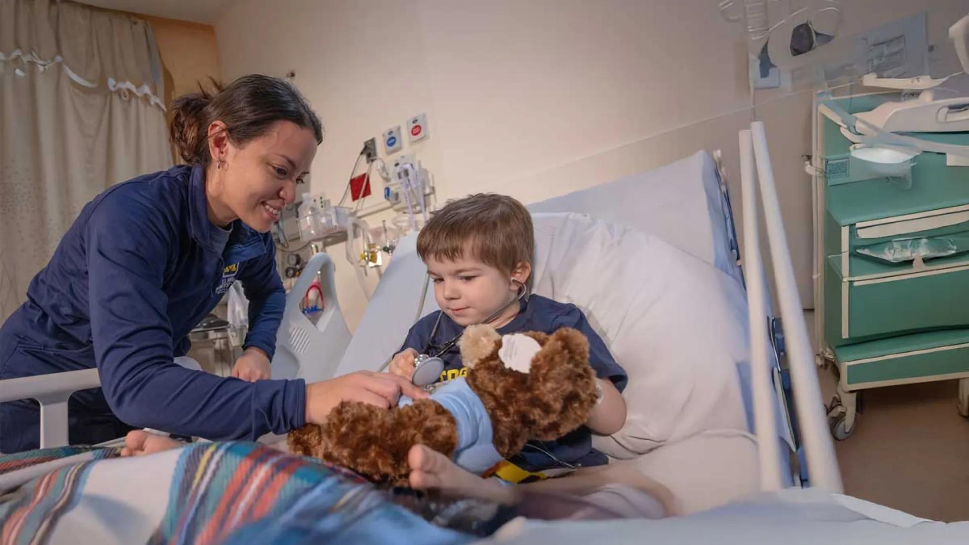A little boy is laying on a bed as a doctor examines him