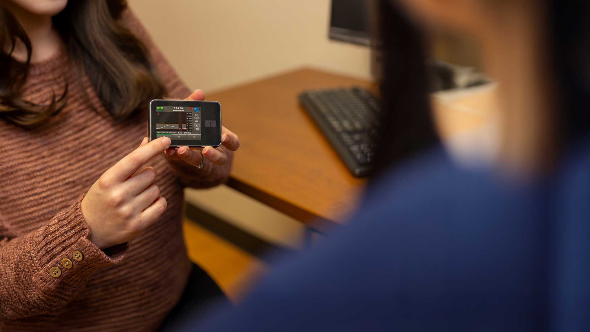 A women shows a patient a diabetes monitor