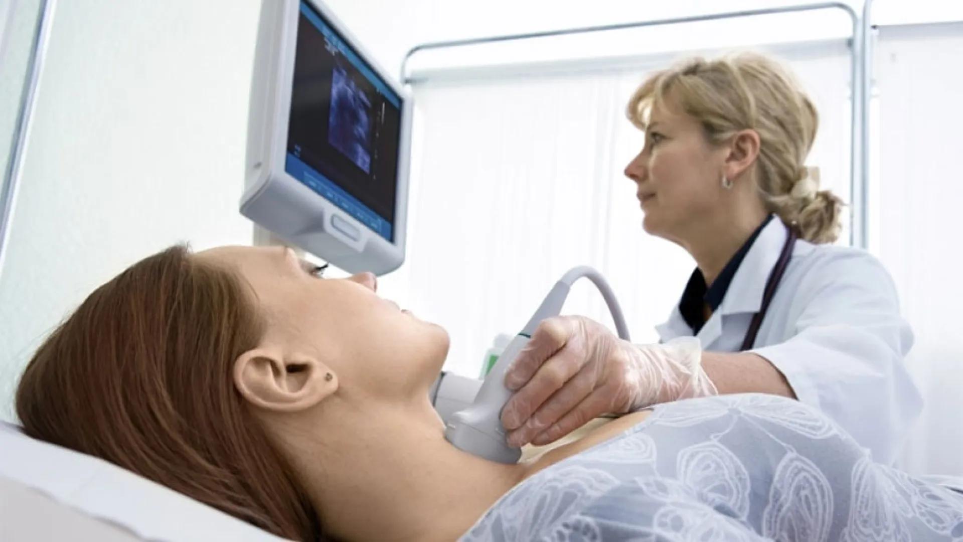 Female patient has her thyroid scanned by a female doctor