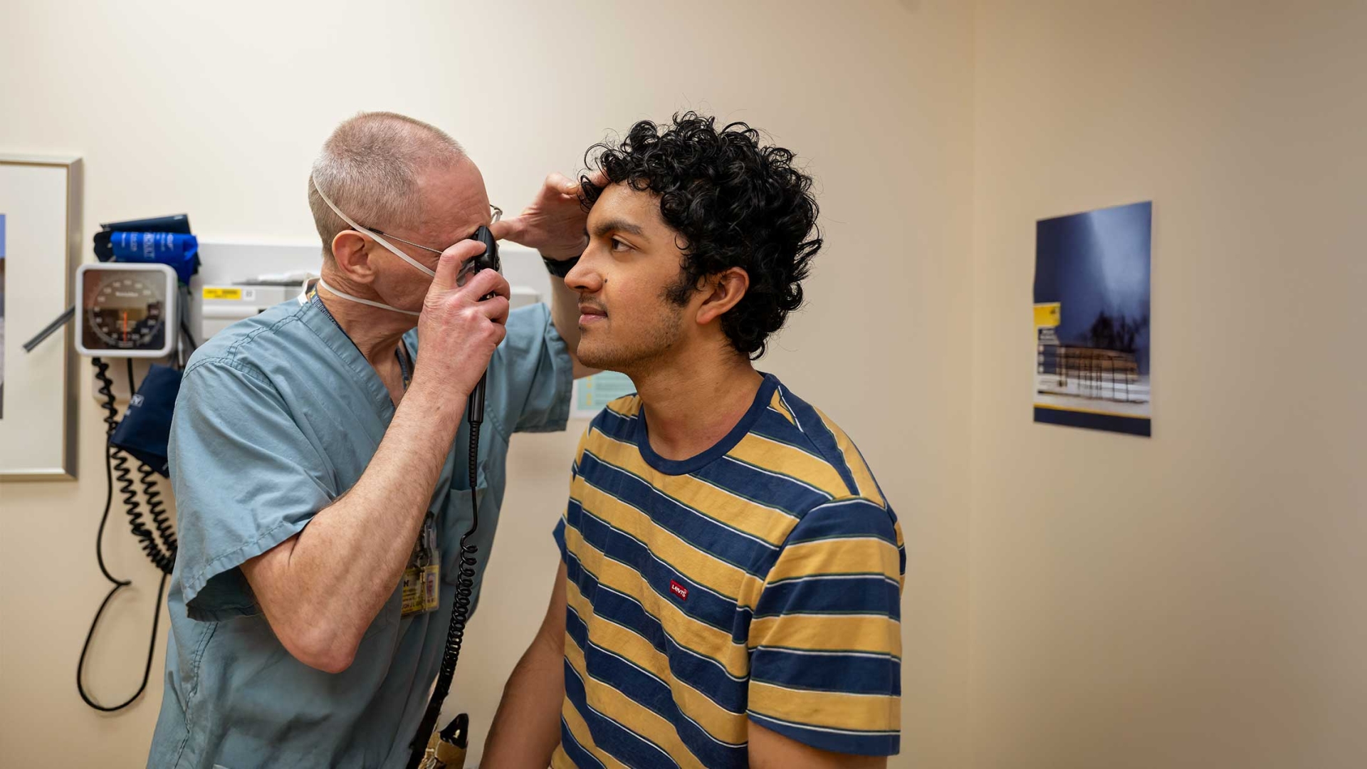 A physician looks in a teenage boys eyes to examine them.