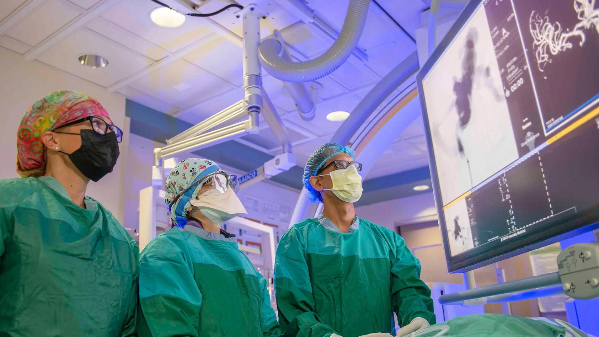 neurosurgeons in scrubs examine data on computer screen