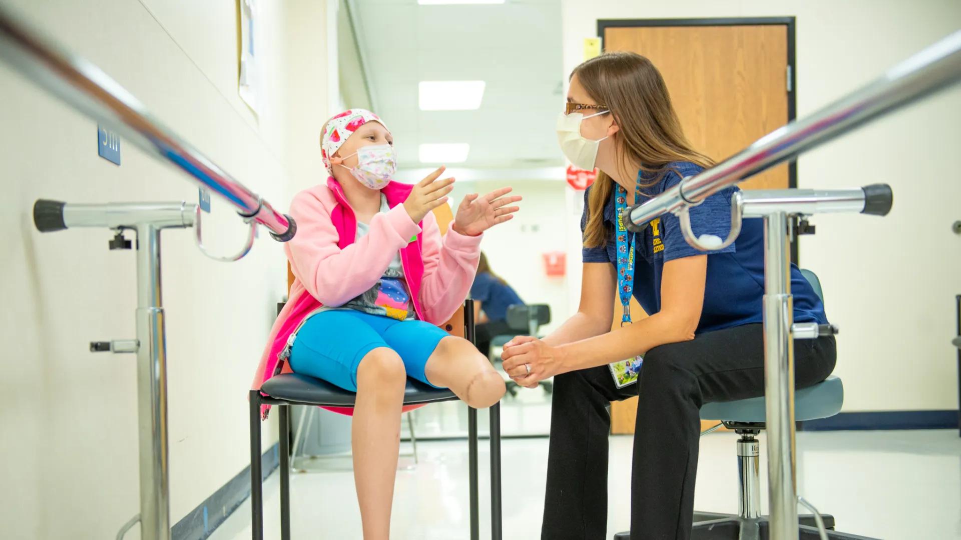 Pediatric rehabilitation patient sits in a char talking with a provider