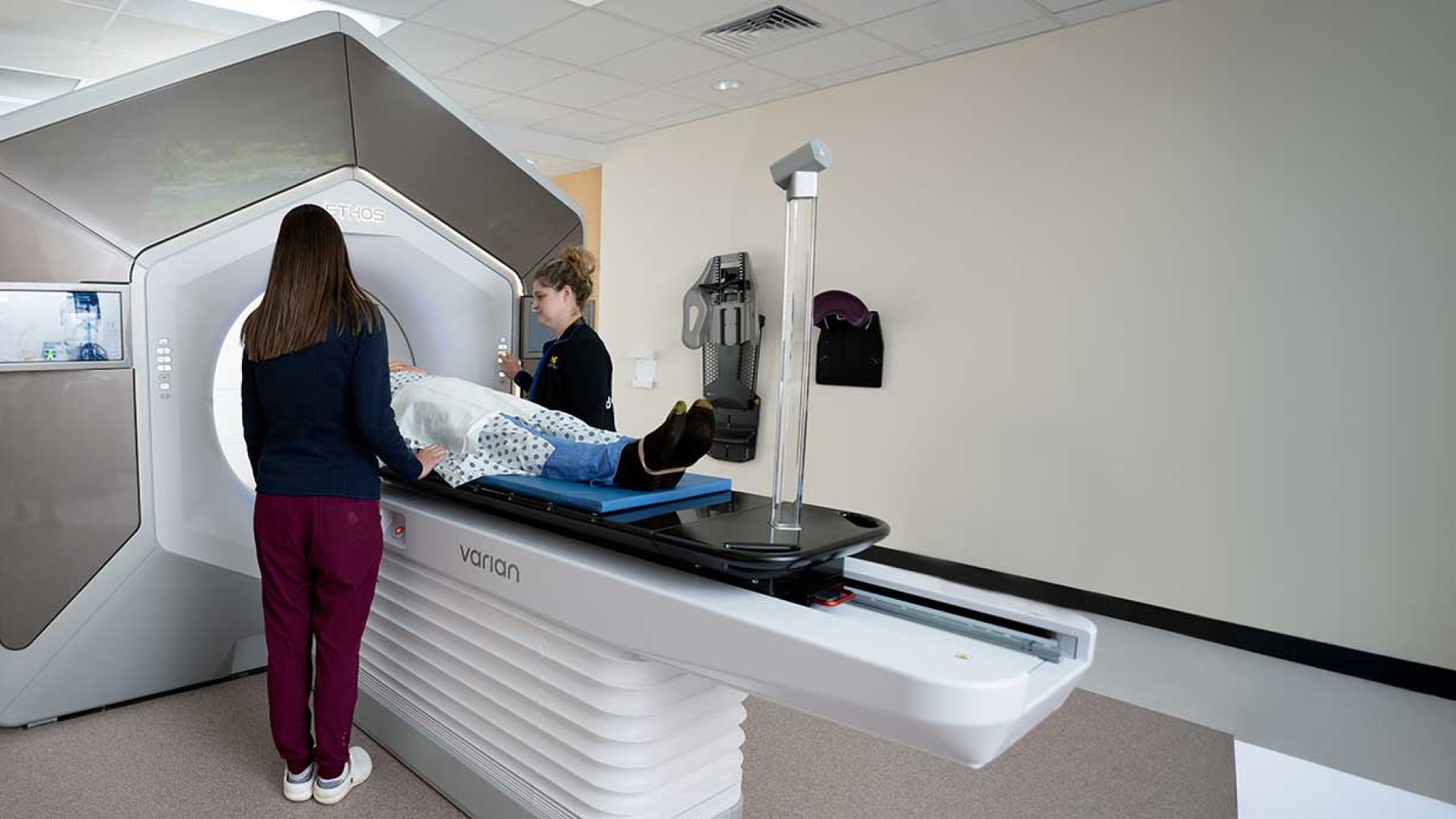 Two female radiation oncology technicians work with a patient