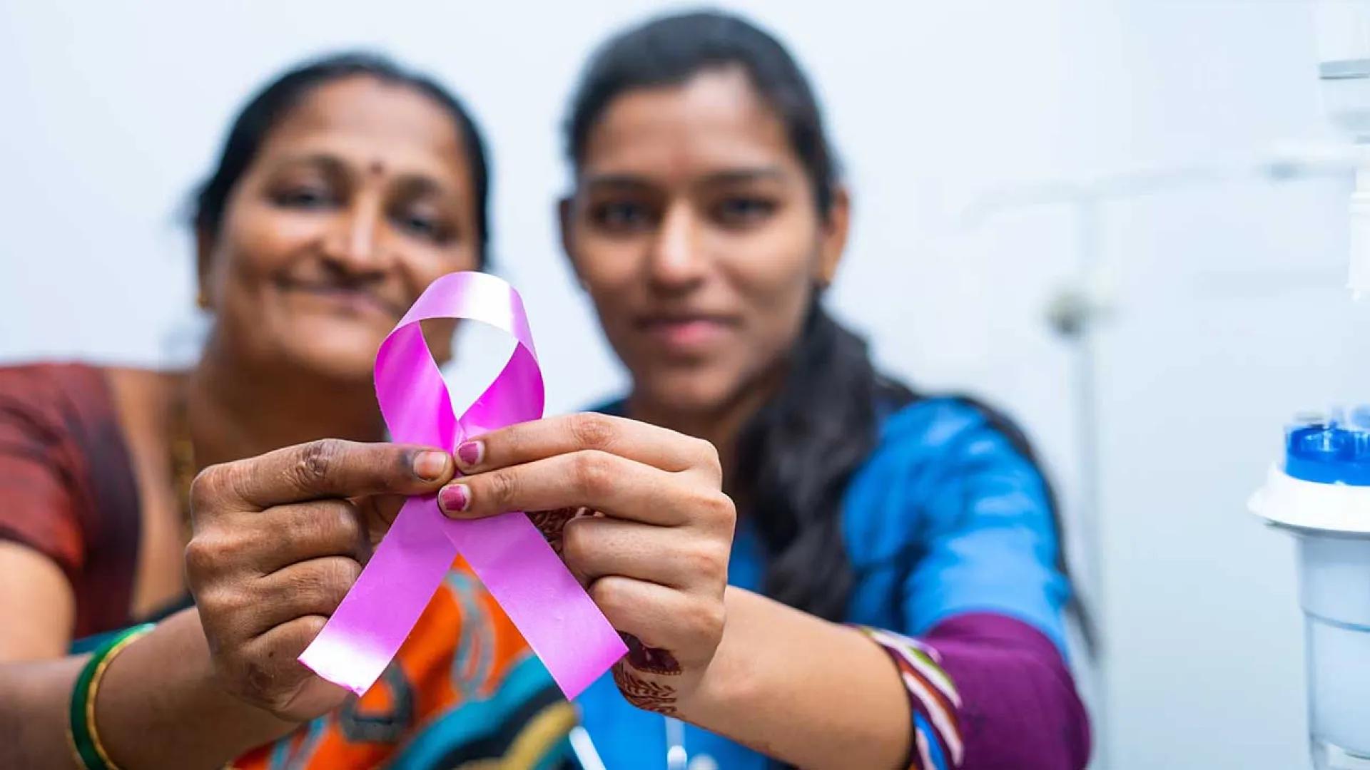 Indian mother and daughter hold a breast cancer awareness ribbon