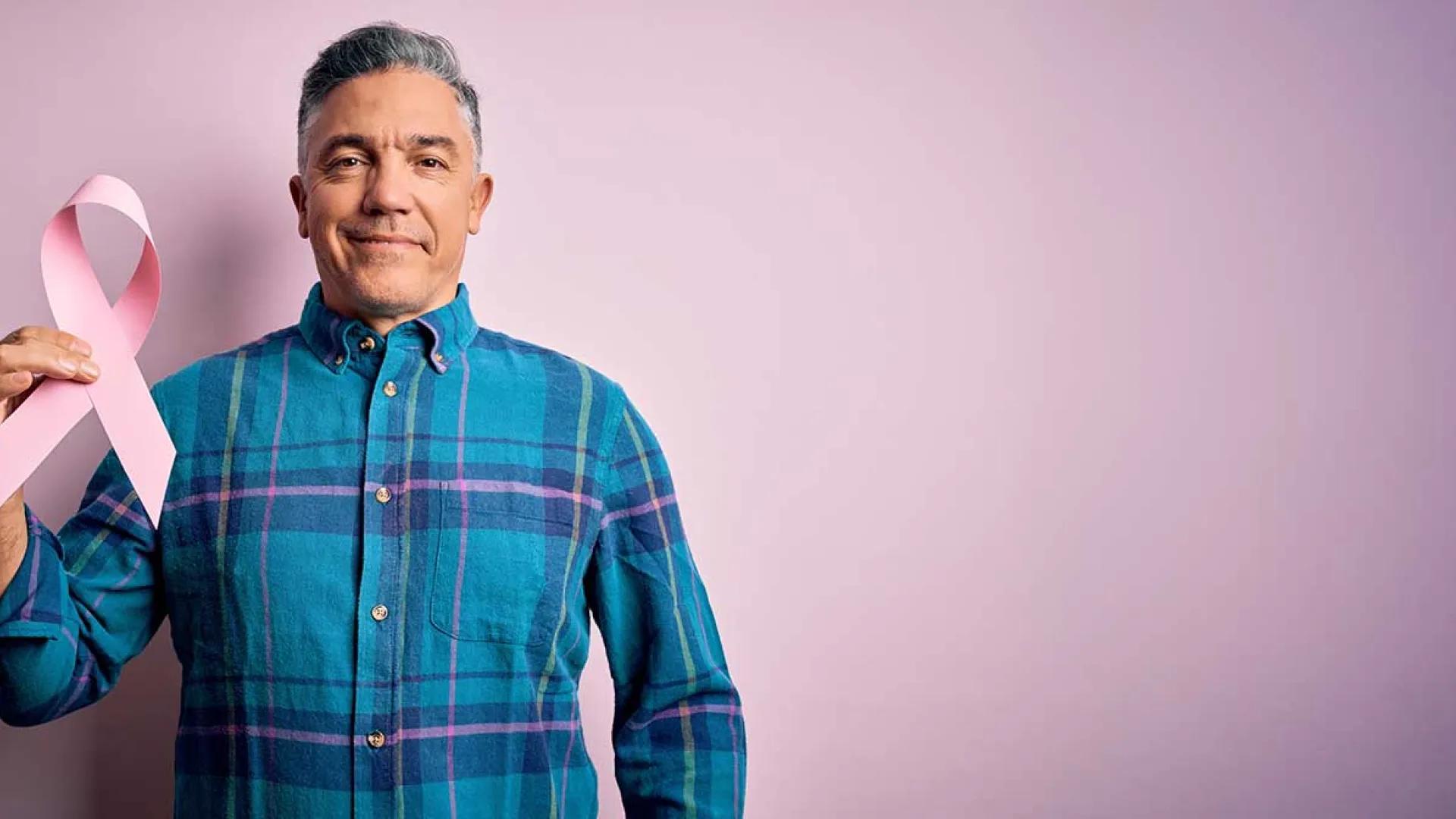 Mature Hispanic male holds pink breast cancer awareness ribbon
