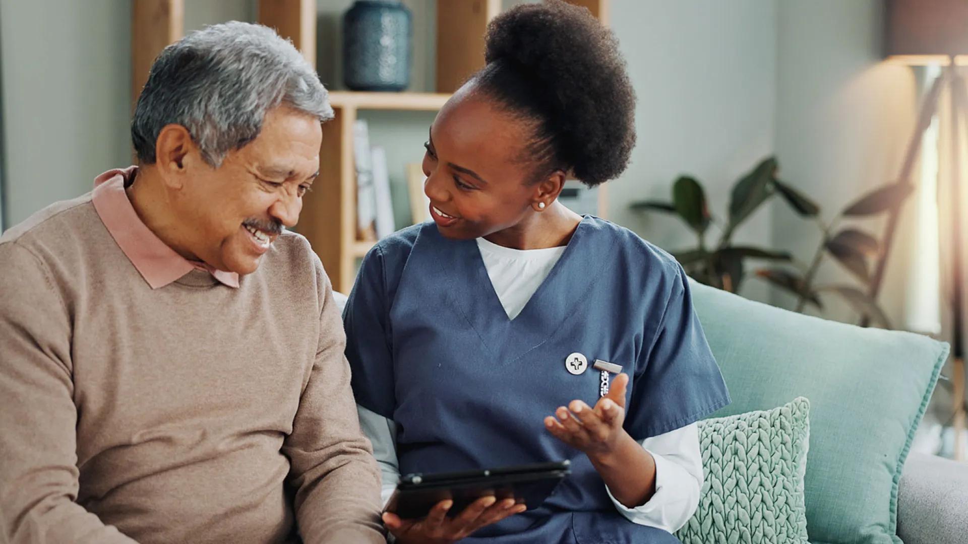 Black female nurse shows an older male patient how to access information online