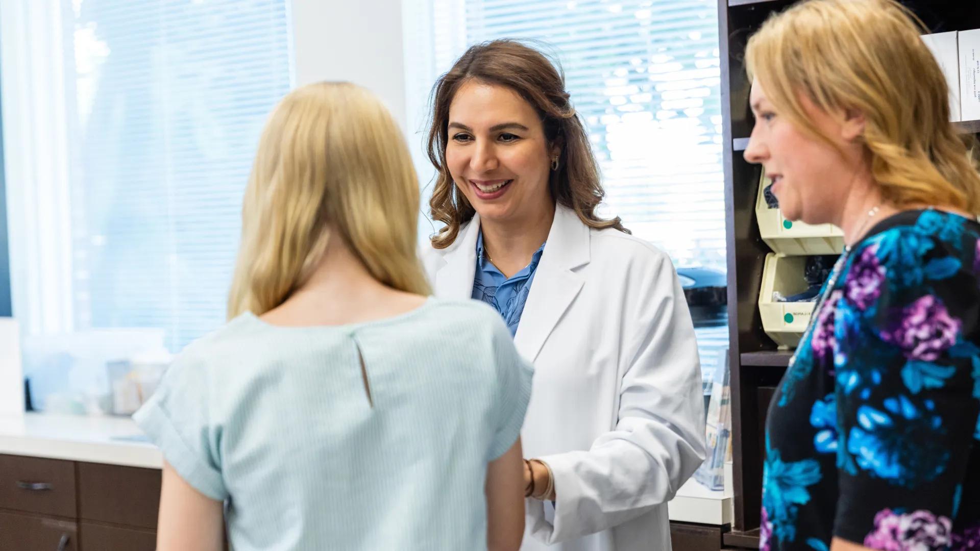 female provider speaks with teen girl, smiling
