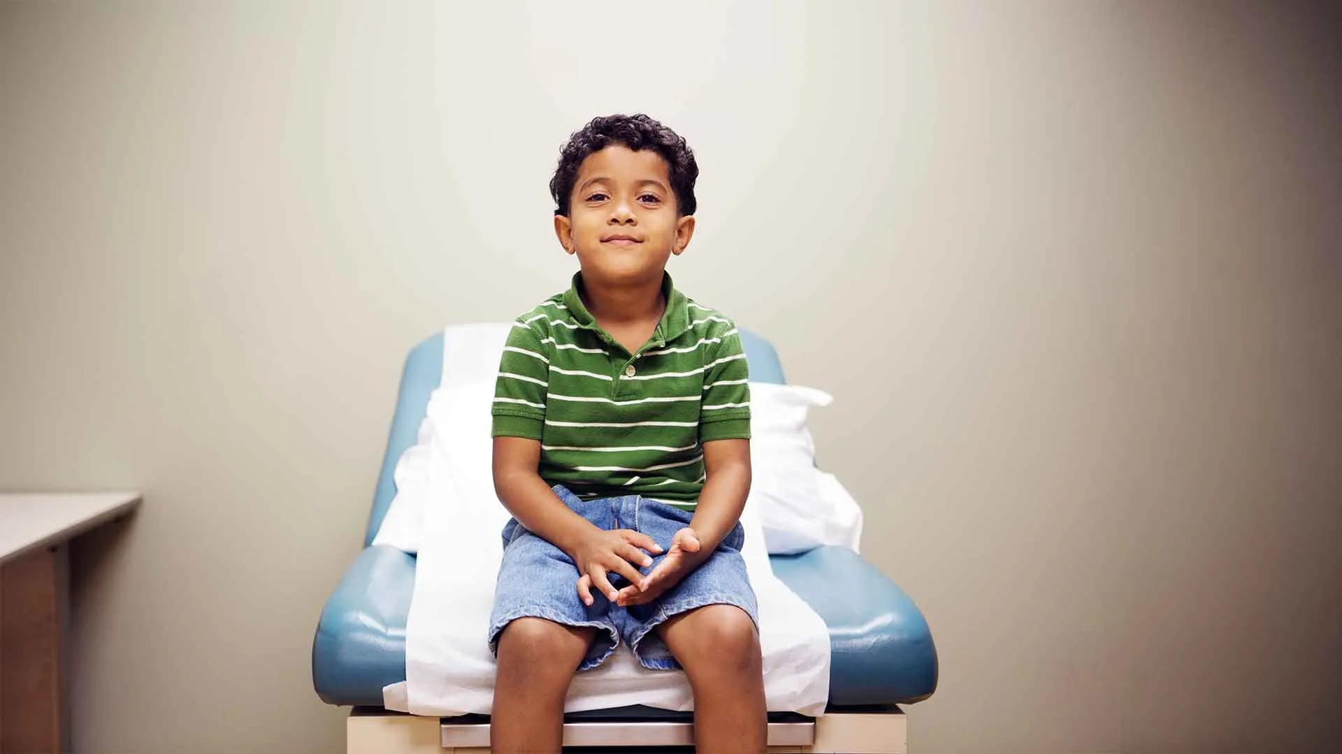 A child sits on a medical table in a doctor's office.
