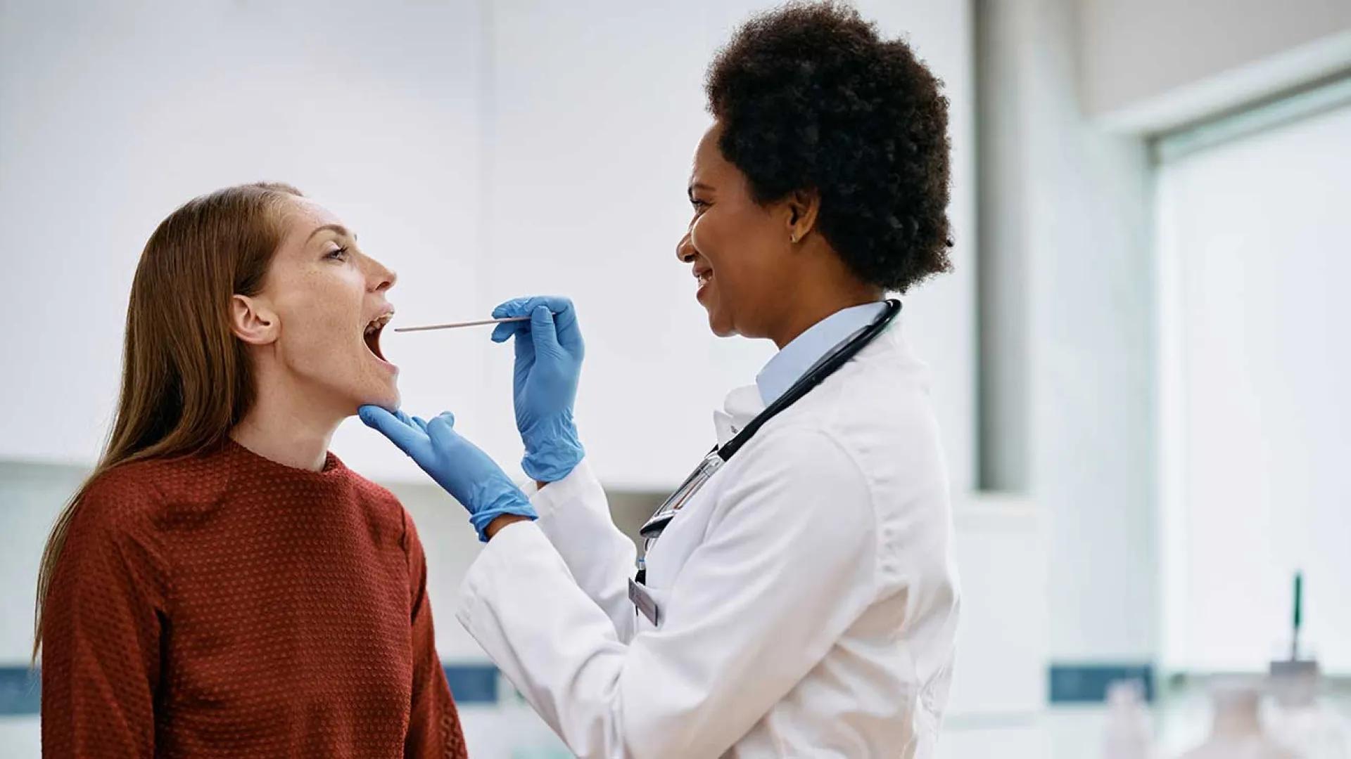 Black doctor checks female patient's throat