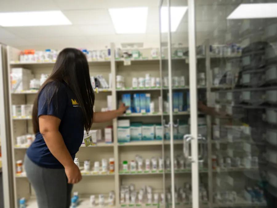 Woman with long dark hair reaching for a prescription medication