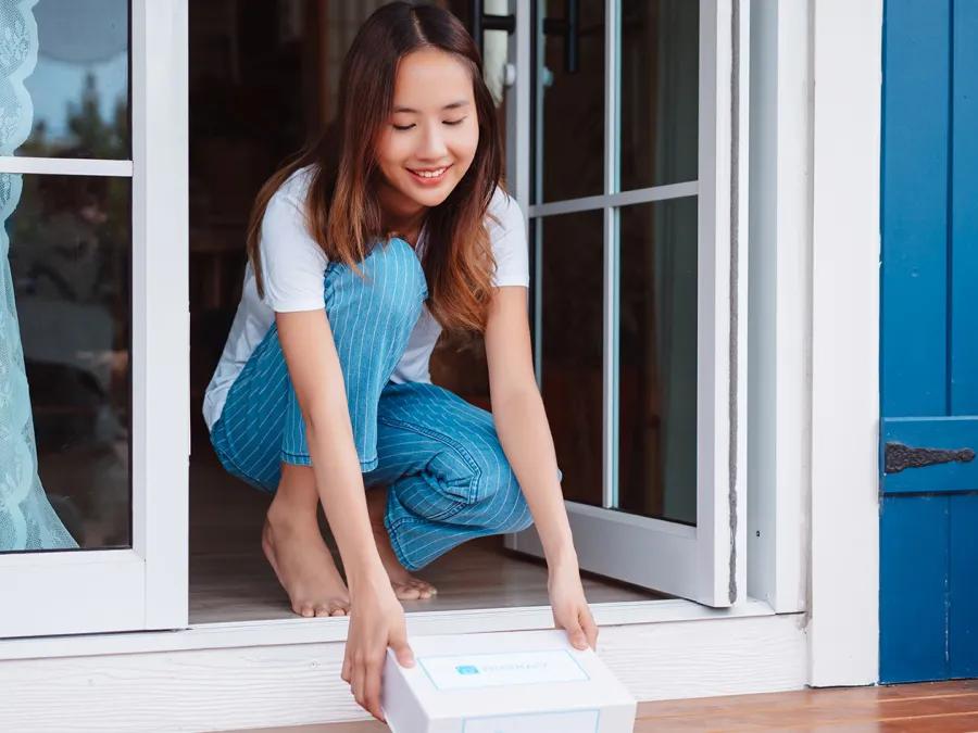 Person bending down to pick up a box from their doorstep