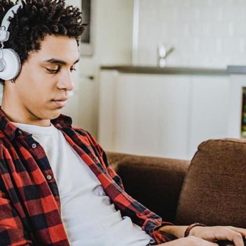 Teen boy with headphones on looking at his phone