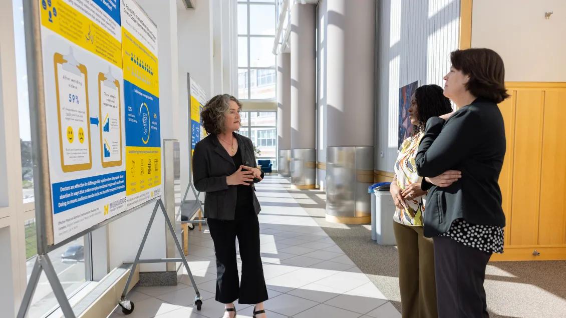 a group of women standing in front of a poster