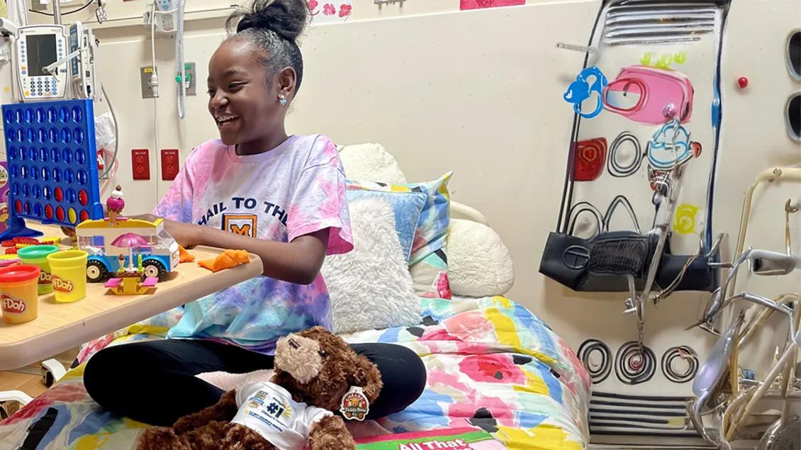 Smiling Black girl playing with colorful toys in hospital bed