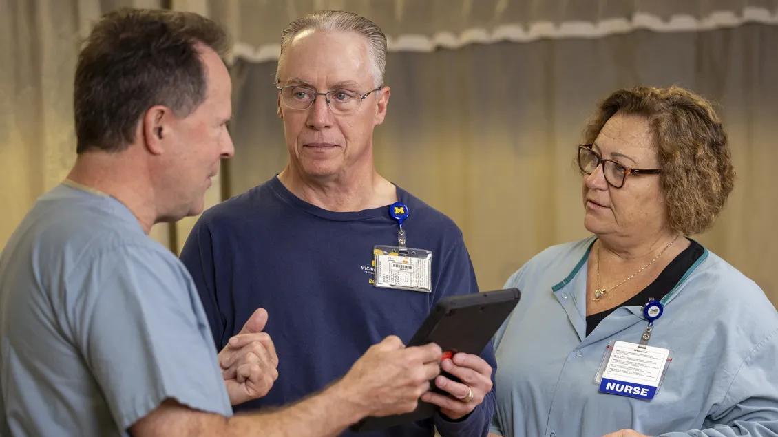 A man talking to two of his care providers in a clinic setting.