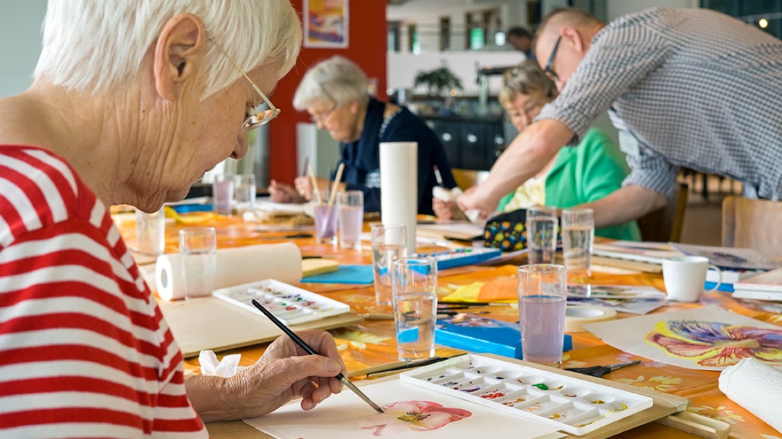 A group of mature men and women create art together