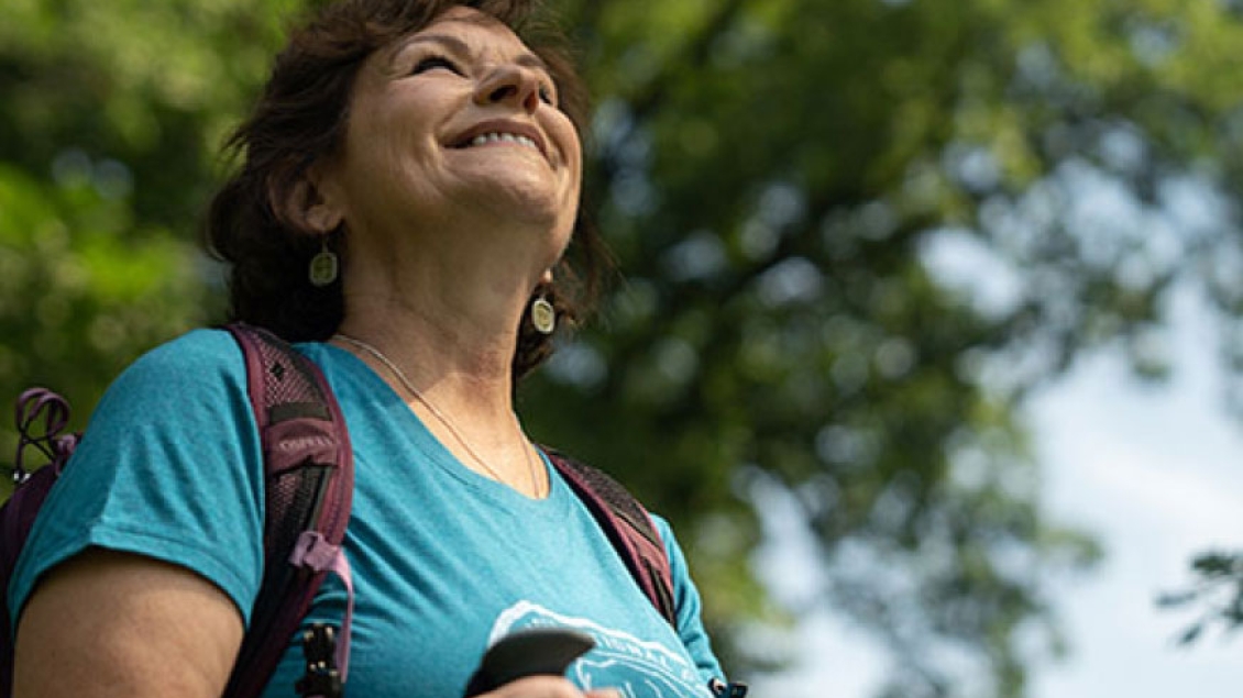 Mature woman hiker smiles up into the sunshine