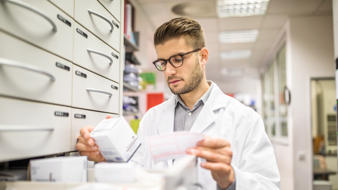 Pharmacist checking medicines on rack. Chemist searching the medicines at storage self.