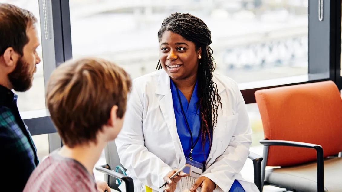 female doctor speaks to male patient/family in waiting room