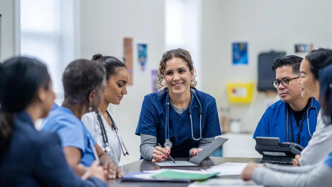 6 Healthcare providers smile during a meeting at a table