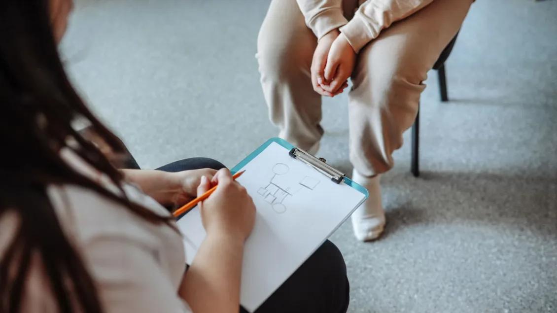 close-up of two people speaking in therapy, hands on clipboard