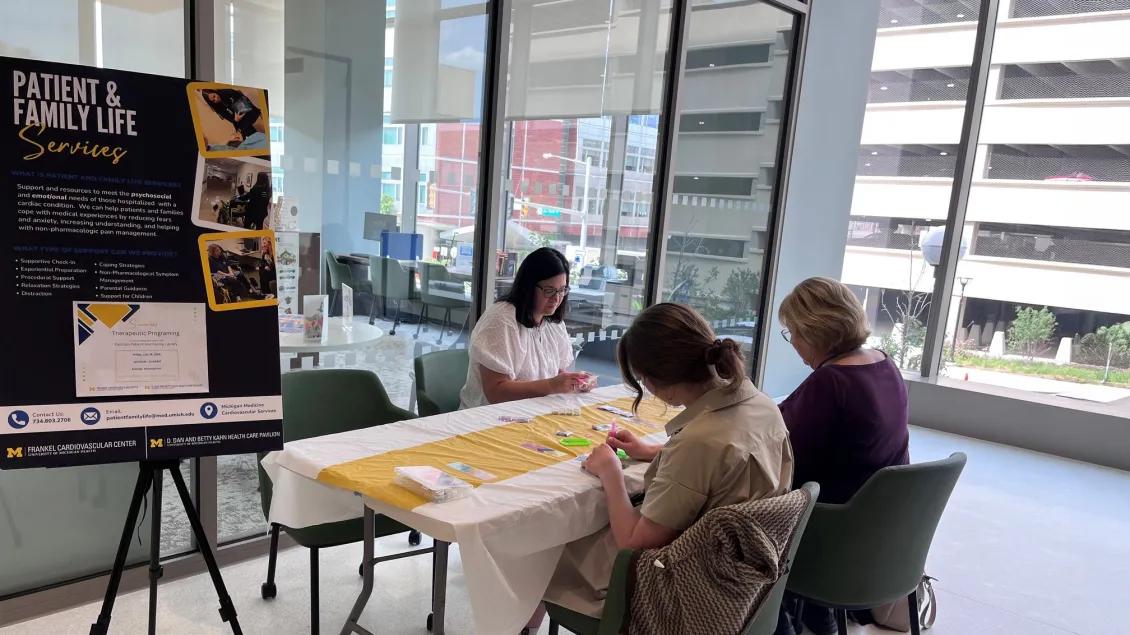Sign displaying text "Patient & Family Life Services" with 3 women seated at a table to the side