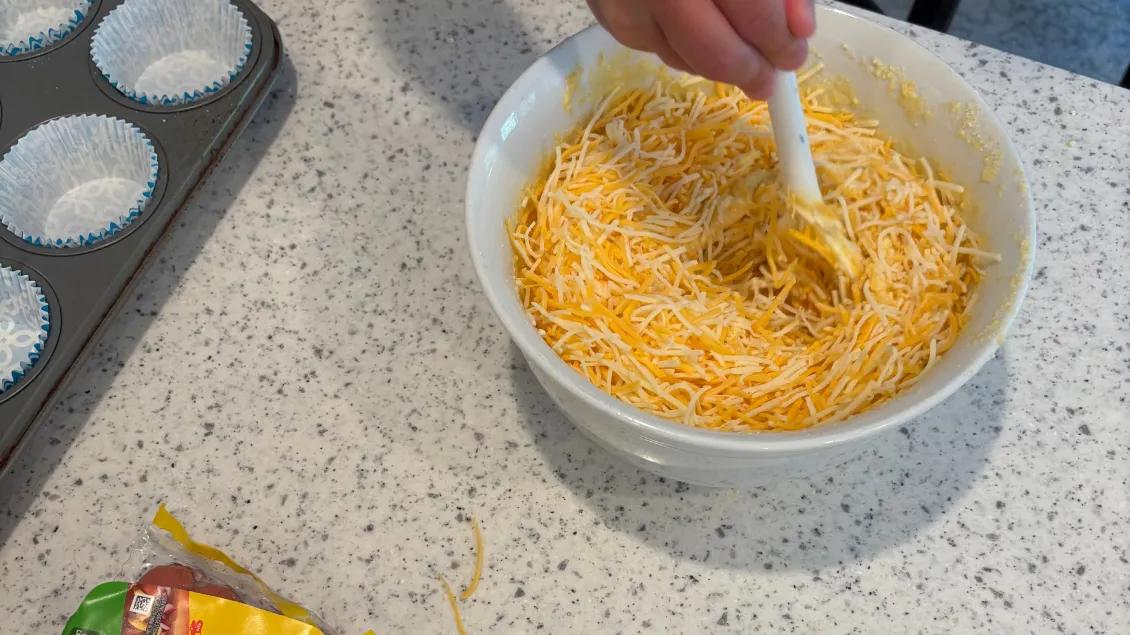 boy stirring cornbread mix with cheese shredded inside