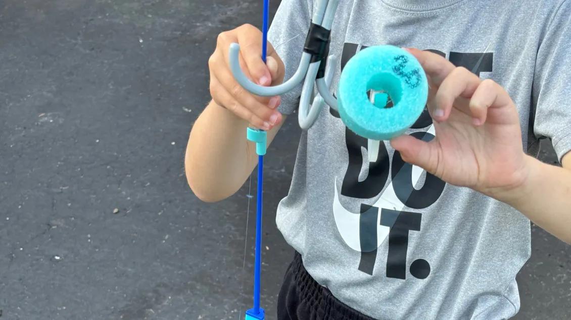 boy holding up pool noodle piece with number 20 on bottom