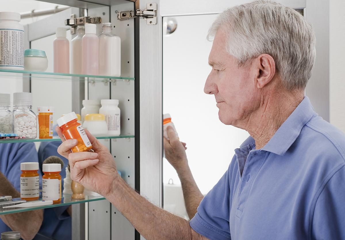 Man taking pills from medicine cabinet