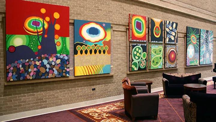Collection of brightly colored, modern paintings on a hospital corridor wall