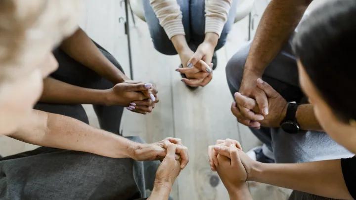 Hands clasped together by five individuals in a circle