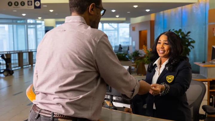 Smiling black woman at reception desk greeting man at Frankel Cardiovascular Center