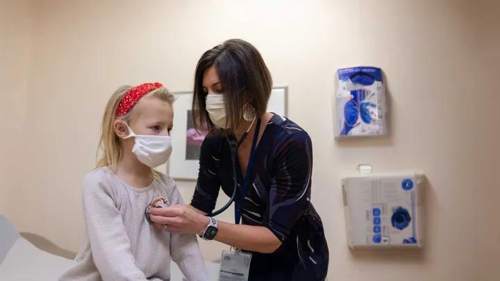 A doctor listens to a pediatric patient's heart with a stethoscope.