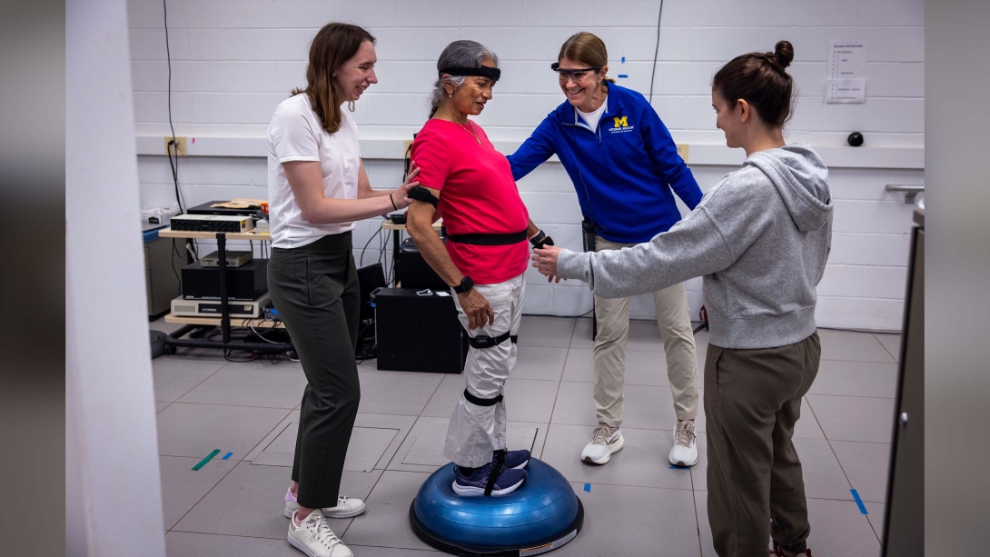 women on balancing ball in PT with three people around her one wearing specialized glasses