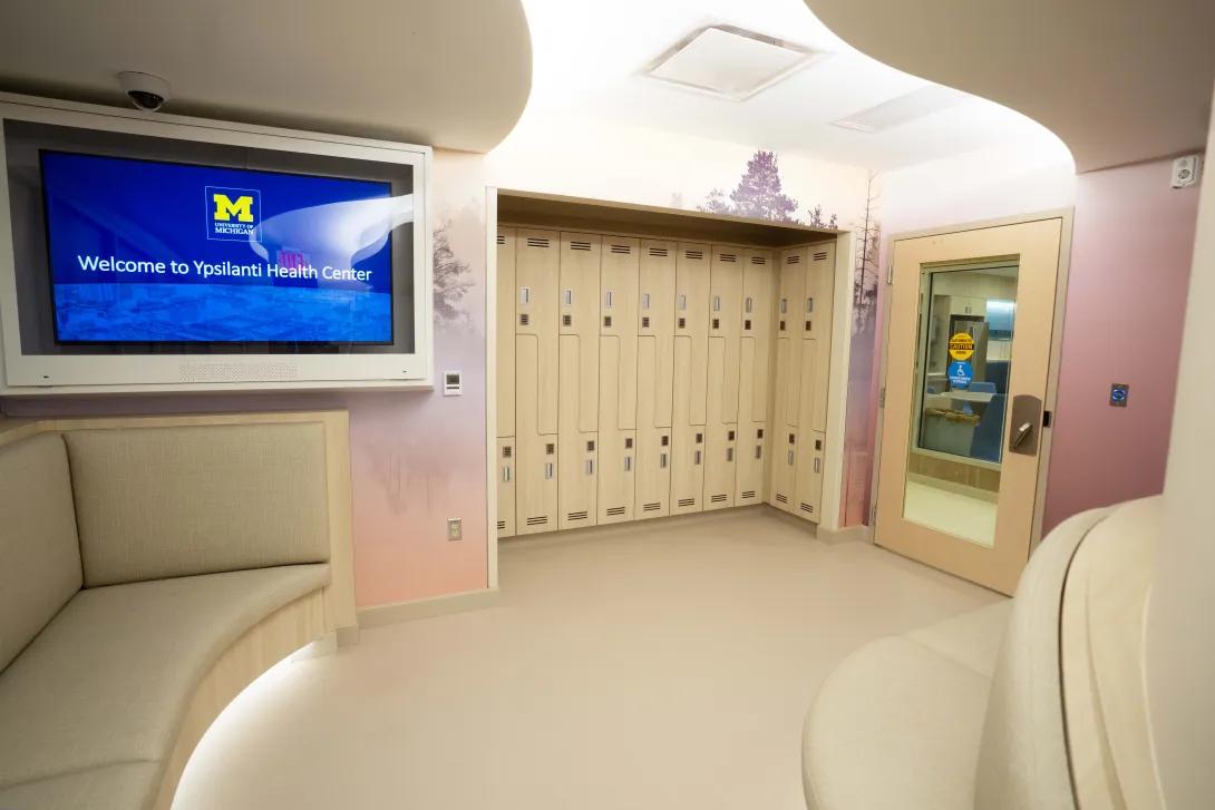Lounge area with lockers and a TV at the Ypsilanti Health Center