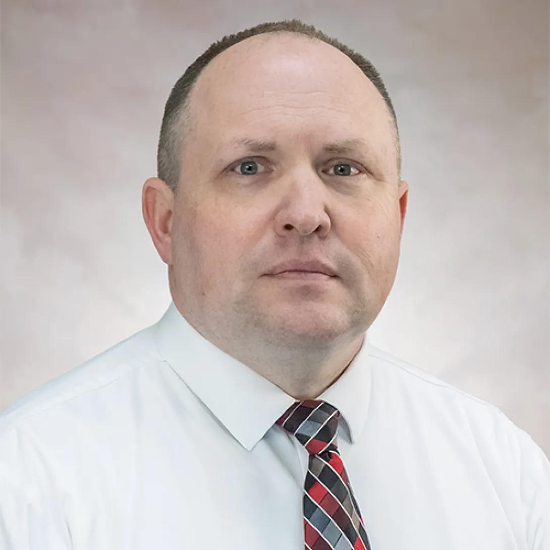 Headshot of Todd Belding, white man wearing white shirt and patterned tie