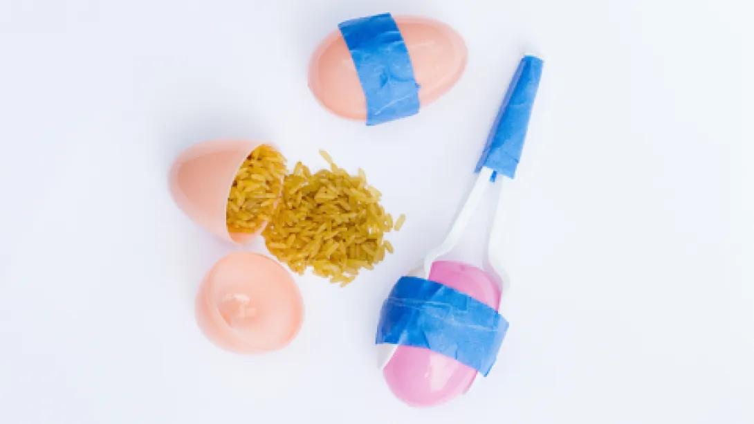 A picture showing homemade maracas ingredients - Rice, Plastic spoons, Painter’s tape, Easter eggs.